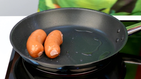 Cook Puts a Few Sausages in Butter on a Frying Pan