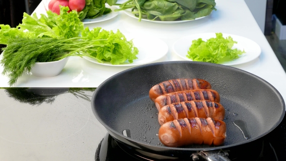 Cook Moves Fried Sausages From a Frying Pan To a Plate