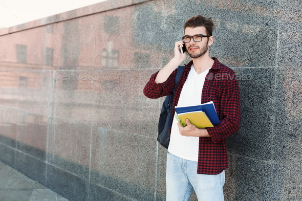 Student talking on phone on grey background - Stock Photo - Images