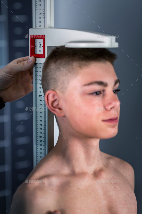 Physical Therapist measuring height of teenage boy.