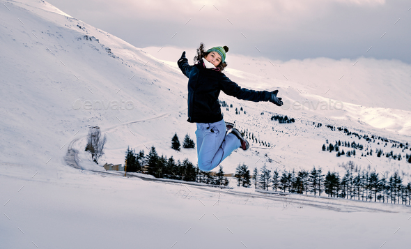 Happy woman jumping in the snow - Stock Photo - Images