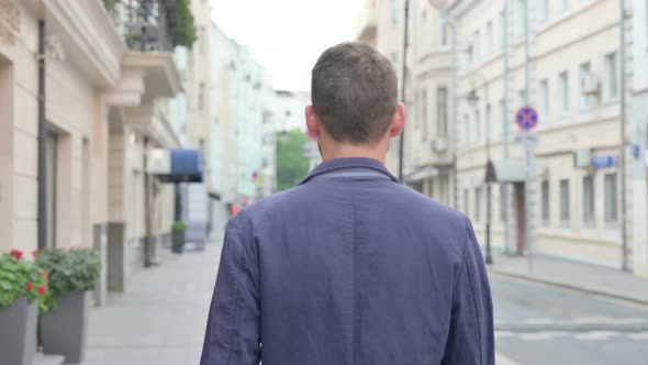 Back View of Mature Adult Man Walking in a Street alt