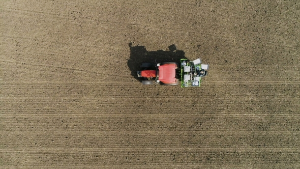 Red Tractor Mounted Seed Drill Plants the Seeds in the Soil in the Experimental Field. Aerial View alt