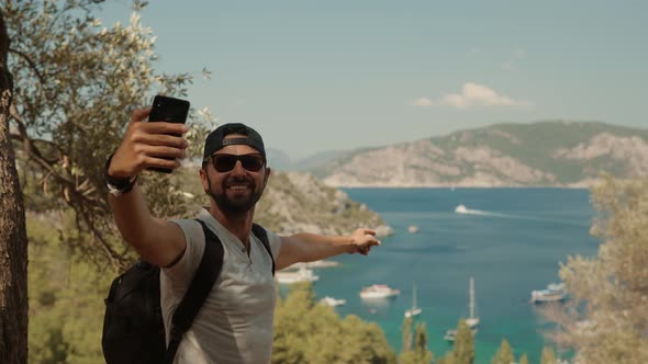 Man Using Mobile Phone For Selfie Photo. Selfie On Smartphone In Beautiful Place. Tanned Man. alt