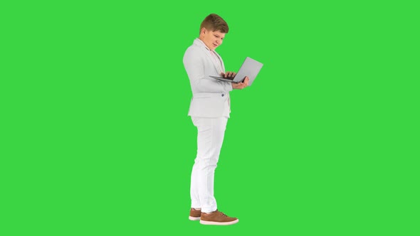 Caucasian Boy in a Suit Working on Laptop on a Green Screen Chroma Key alt