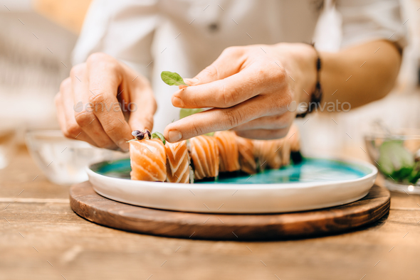 Male person cooking sushi rolls with salmon - Stock Photo - Images