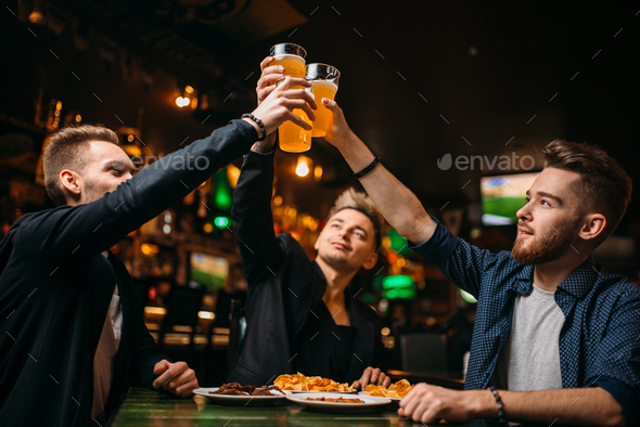 Fun company raised their glasses in a sport bar - Stock Photo - Images