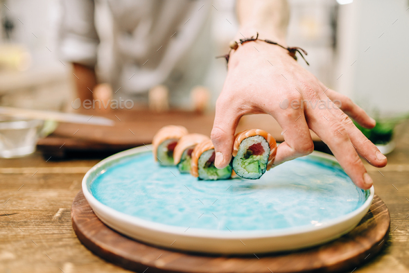 Male person cooking sushi rolls on wooden table - Stock Photo - Images