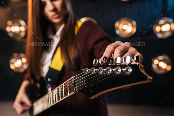 Female rock guitarist in suit tunes the guitar - Stock Photo - Images