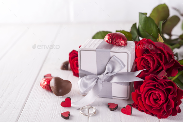 Fresh red roses and gift box on wooden table - Stock Photo - Images
