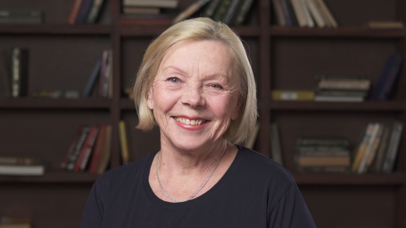 Happy Elderly Cauvasian Woman Smiling Against Bookshelf