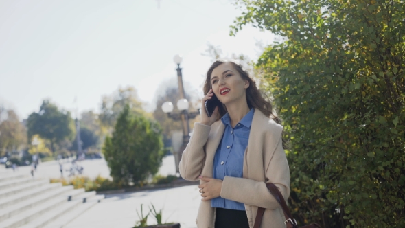 A Beautiful Girl in a White Coat Speaks By Phone