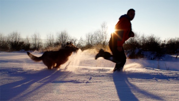 Dog and Man Running in the Snow