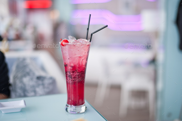 Glass of cherry soda with ice at cafe indoors