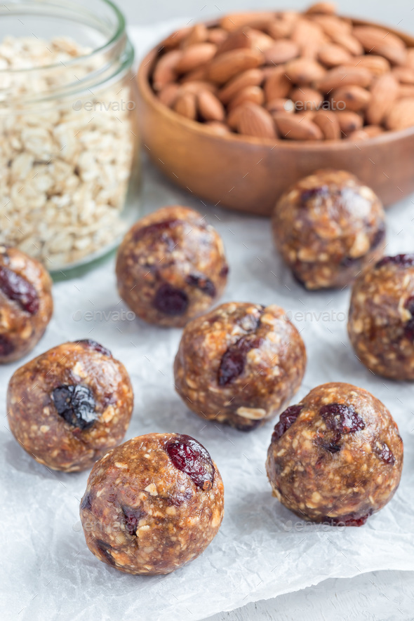 Healthy homemade energy balls with cranberries, nuts, dates and rolled oats on parchment, vertical