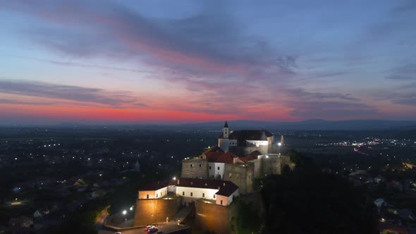 European Castle on Mountain at Night with Beautiful Red Sunset in Summer Season Aerial View alt