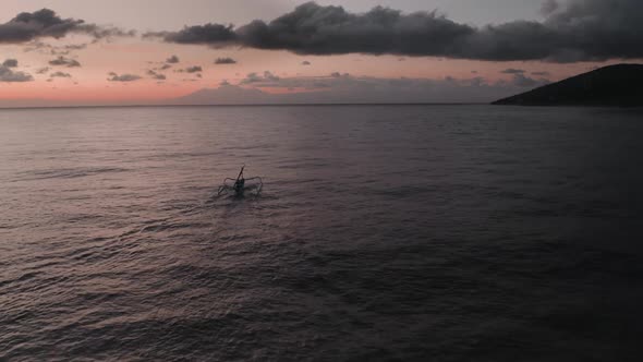 Aerial View of Sunrise Above Ocean with Dark Silhouettes of Fishing Boat Going for Fishery
