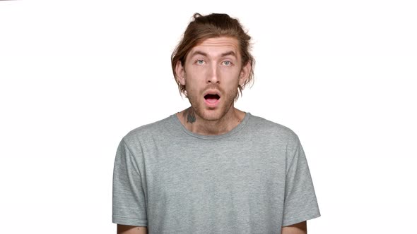 Portrait of Surprised Guy 20s with Tied Hair Covering Open Mouth with Hand and Staring Wideeyed in alt