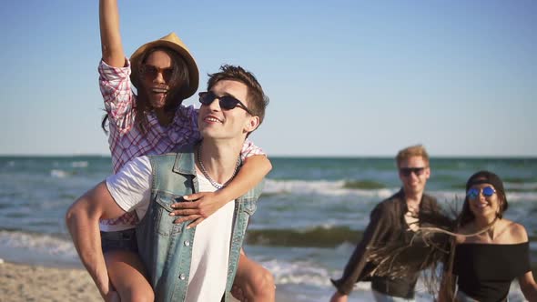 Couple Having Fun Doing Piggyback Together with Young Group of People Laughing Happy Joyful and alt