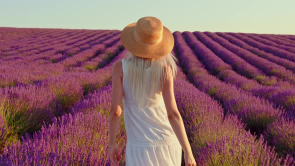 Young Woman in White Dress Walking Through a Lavender Field on Sunset