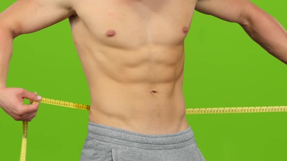 Man Without Shirt Measures Volume of His Waist. Green Screen alt