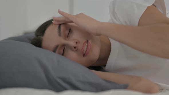 Hispanic Woman having Headache while Sleeping in Bed, Side Pose alt