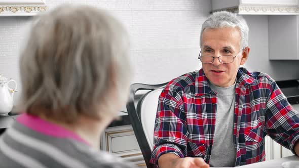 Enthusiastic Aged Male Talking with Mature Wife at Kitchen Having Positive Emotion alt