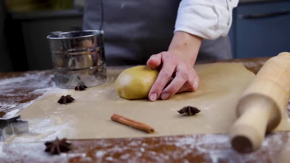 The dough lies on parchment, in the hand of a pastry chef, who sprinkles flour on top of it, a rolli