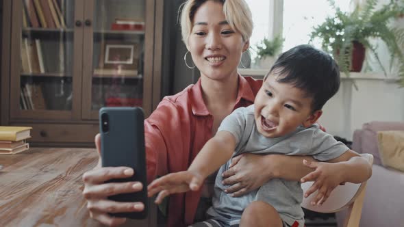 Asian Mother and Little Son Taking Selfie on Smartphone alt