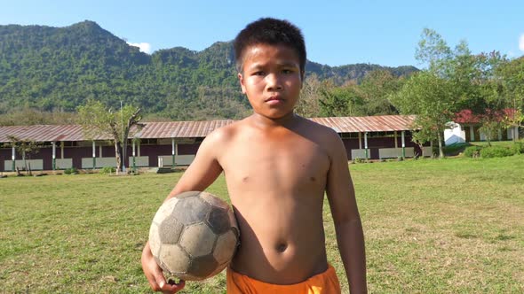 Rural Boy Walking With Old Soccer Ball alt