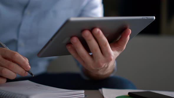Entrepreneur Man Using Tablet Writing Notebook Information Research in Workplace alt