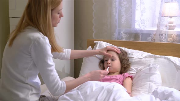 Woman is Measure the Temperature of Little Girl alt