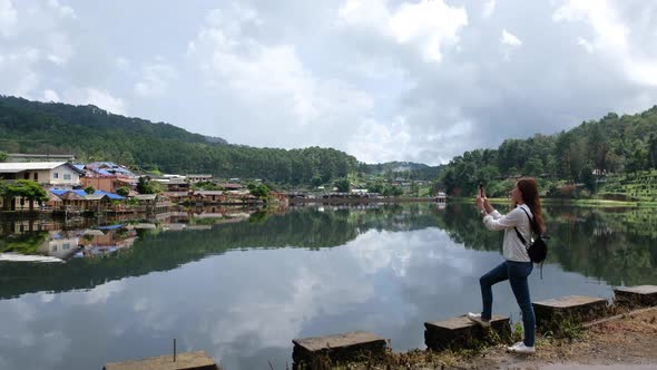 A female tourist shooting video of a beautiful lake