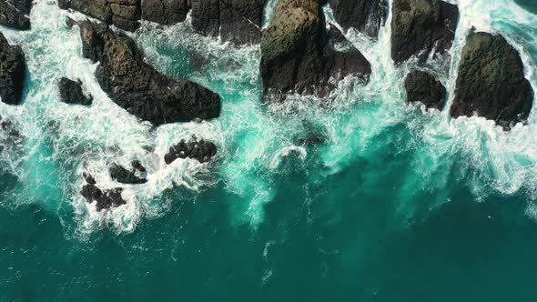 ocean blue waves break on high cliff of a rocky mountain. alt