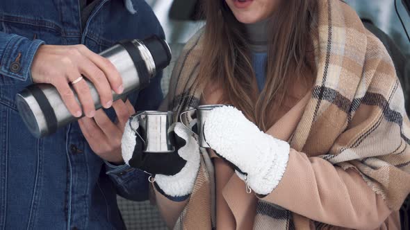 Couple drinking tea. Metal cups from a thermos on the nature in Valentine's day