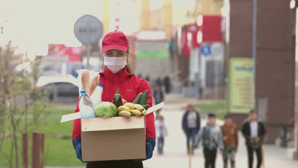 Courier girl with box of food on street. Coronovirus pandemic