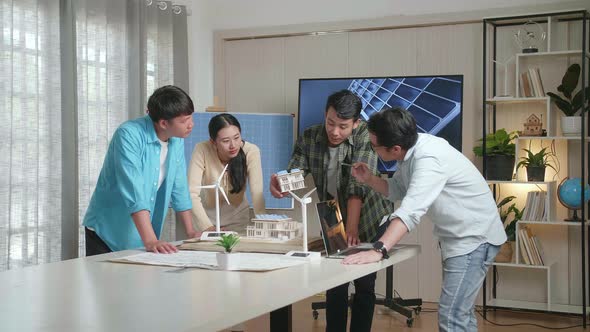 Asian Engineers Group Having A Meeting About The Model Of A Small House With Solar Panel alt