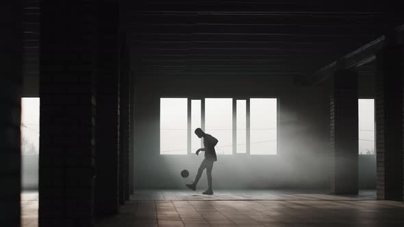A Black Man Makes a Football Freestyle with a Ball in an Underground Parking Lot in the Sunlight alt