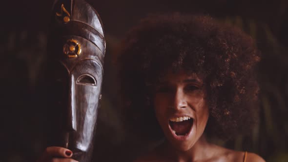 Woman With Afro Holding And Posing With Traditional Mask alt