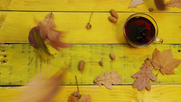 Golden Autumn Background With Foliage And A Mug Of Red Tea On A Yellow Wooden Table
