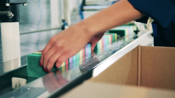 Factory Worker Loading Scrub Sponges Onto a Conveyor at a Factory alt