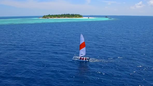 Aerial drone view of a man and woman sailing on a boat to a tropical island. alt
