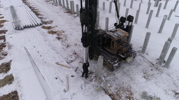 Aerial drone view of a pile bore machine at work at winter construction site 10 alt