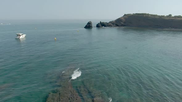 Man Is Standing on a Rock Cliff Above a Blue Sea alt