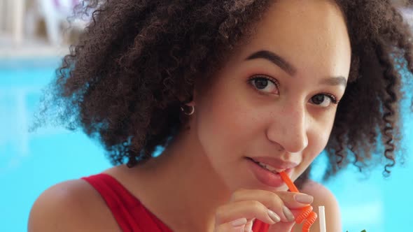 Close View Portrait of Curly-haired Brunette of African Ethnicity Standing Sitting on Blue alt