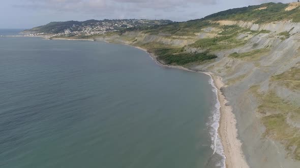 Backtracking aerial of Charmouth beach looking west along to Lyme Regis. Home of the UK fossil hunti alt