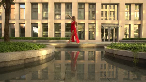 Beautiful Young Girl Dancing on the Street of a Modern City and Is Reflected in the Water alt