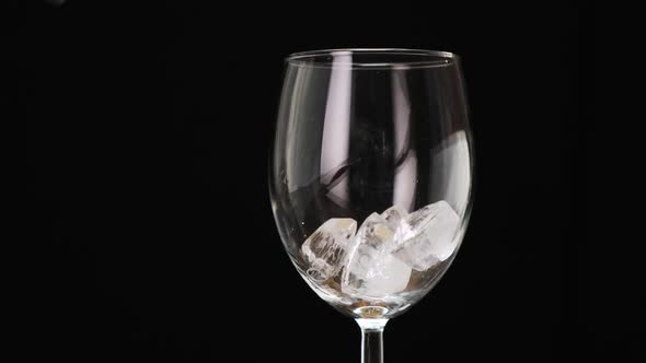 Pour ice cubes into a glass on black background. Close up. HD