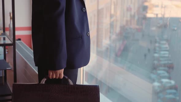 Kid Boy Boss in Suit with Briefcase in His Hand is Looking at Window in His Office alt