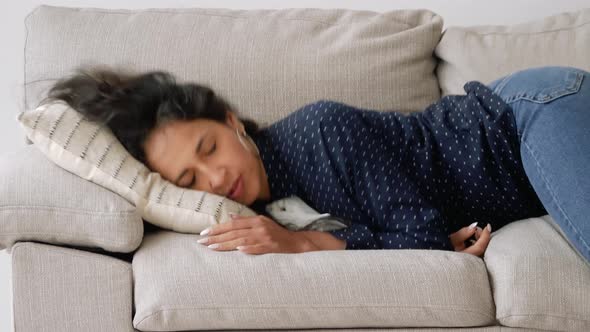 Sleepy mixed race woman falls down on sofa. Exhausted, bored, apathetic girl.